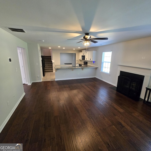 590 Dot Dr, Atlanta, GA 30349 - unfurnished living room featuring dark wood-type flooring, stairway, baseboards, a fireplace with flush hearth, and recessed lighting