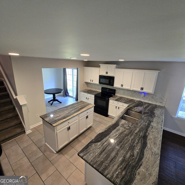 590 Dot Dr, Atlanta, GA 30349 - kitchen with black appliances, a sink, a kitchen island, baseboards, and a peninsula
