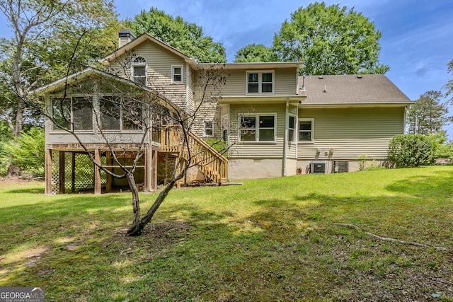 back of property with a chimney, a yard, stairs, and a sunroom