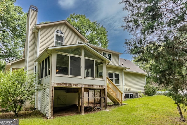 rear view of property featuring a sunroom, a chimney, stairs, and a yard