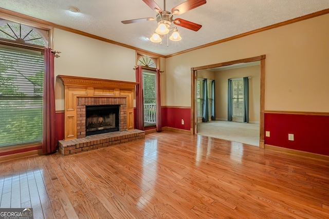 unfurnished living room with wood finished floors, plenty of natural light, a ceiling fan, a textured ceiling, and a fireplace