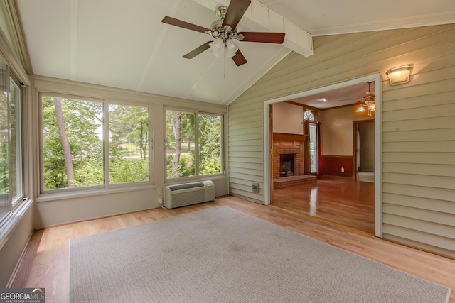 unfurnished sunroom featuring healthy amount of natural light, wood walls, wood finished floors, and a wall unit AC