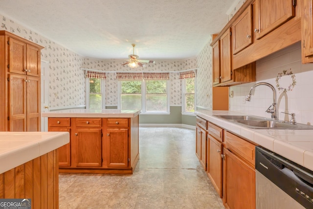kitchen featuring dishwasher, a sink, tile countertops, ceiling fan, and wallpapered walls