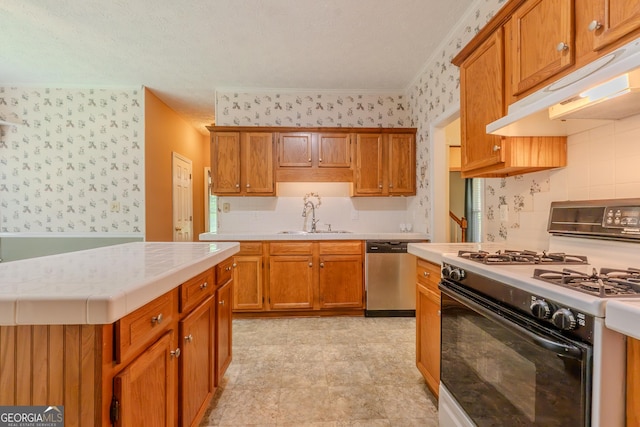 kitchen featuring range with gas cooktop, dishwasher, under cabinet range hood, a sink, and wallpapered walls