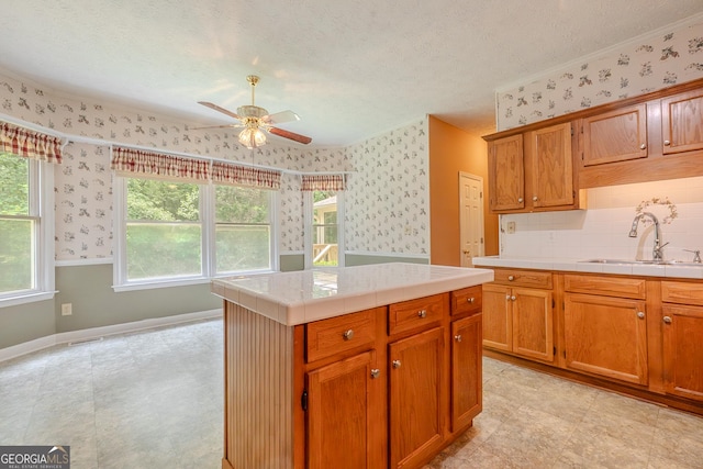 kitchen featuring a sink, wallpapered walls, ceiling fan, a textured ceiling, and tile countertops