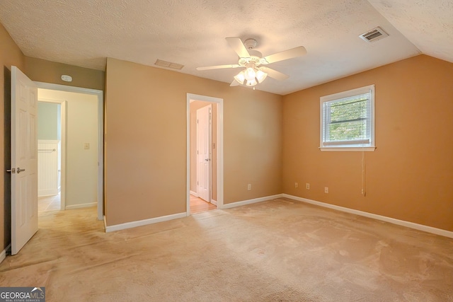 unfurnished bedroom with light carpet, a textured ceiling, baseboards, a ceiling fan, and vaulted ceiling