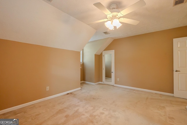 bonus room featuring a ceiling fan, light carpet, baseboards, lofted ceiling, and a textured ceiling