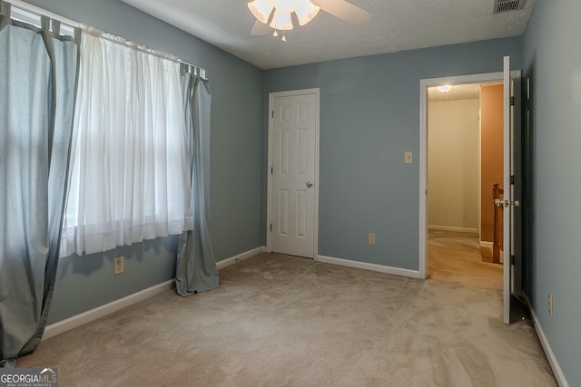unfurnished bedroom featuring light colored carpet, baseboards, and ceiling fan