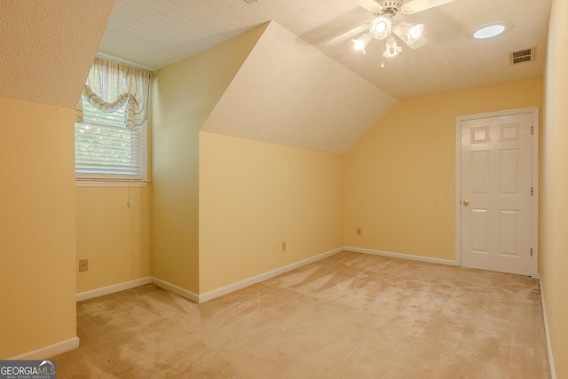 bonus room featuring light colored carpet, lofted ceiling, a ceiling fan, and baseboards