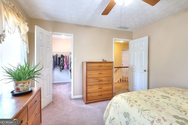 1935 Shrader Ct, Lawrenceville, GA 30044 - bedroom featuring a walk in closet, light colored carpet, a closet, a textured ceiling, and a ceiling fan