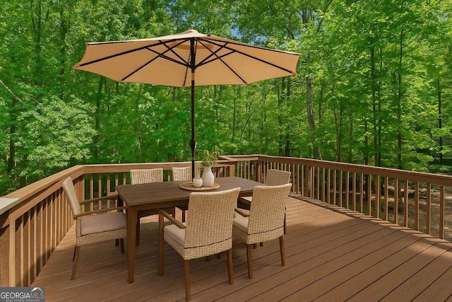 wooden deck with outdoor dining space and a forest view
