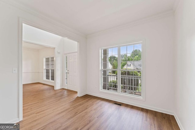 empty room featuring wood finished floors, crown molding, and baseboards
