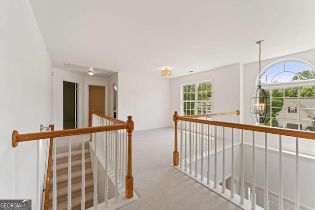 hall featuring an upstairs landing, carpet, and attic access