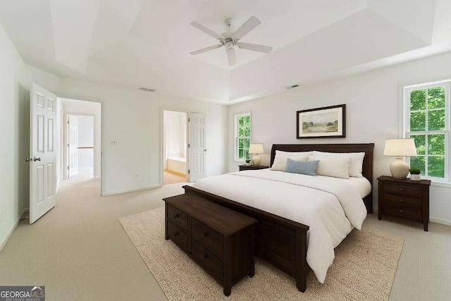 bedroom with light carpet, a raised ceiling, and baseboards