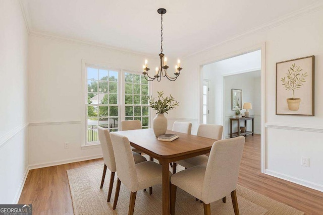 dining space featuring a chandelier, light wood finished floors, crown molding, and baseboards