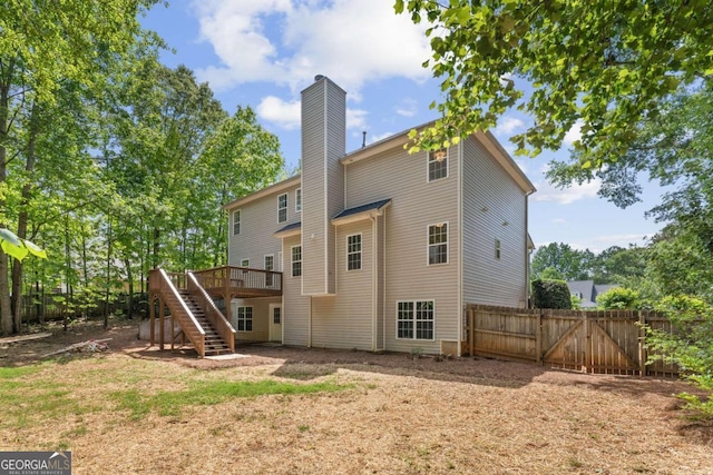 rear view of property with stairs, a chimney, fence, and a deck