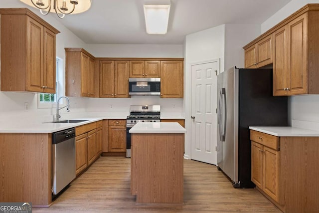 kitchen with stainless steel appliances, a sink, a center island, light wood-type flooring, and brown cabinetry