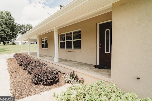 entrance to property with stucco siding and covered porch