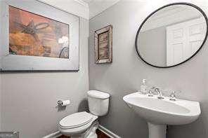 1667 Wehunt Pl SE Unit 11, Smyrna, GA 30082 - half bathroom featuring toilet, baseboards, and a sink