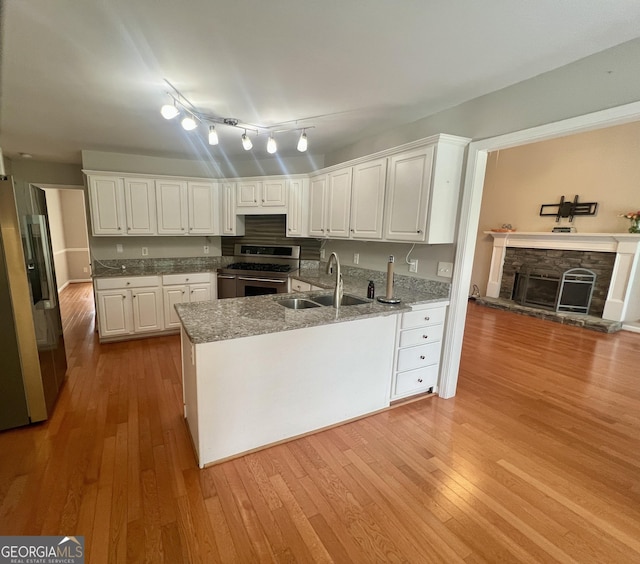 402 Hancock Ct, Woodstock, GA 30188 - kitchen featuring a sink, stainless steel appliances, a fireplace, and light wood-type flooring