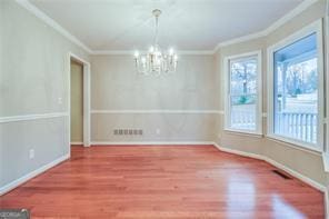 402 Hancock Ct, Woodstock, GA 30188 - unfurnished dining area with ornamental molding, a chandelier, wood finished floors, and baseboards
