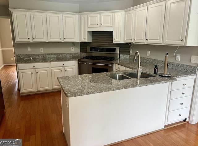 402 Hancock Ct, Woodstock, GA 30188 - kitchen with stainless steel gas range oven, a sink, wood-type flooring, white cabinets, and stone counters