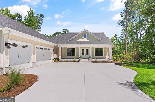 108 Branch Creek Rd, Woodbine, GA 31569 - view of front of home with french doors, driveway, a garage, roof with shingles, and a front lawn