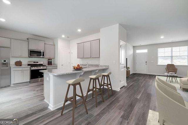 201 Ellie Way, Savannah, GA 31419 - kitchen with appliances with stainless steel finishes, wood finished floors, a kitchen bar, gray cabinetry, and recessed lighting