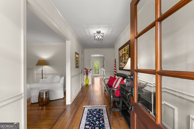hall with ornamental molding, dark wood finished floors, and a chandelier