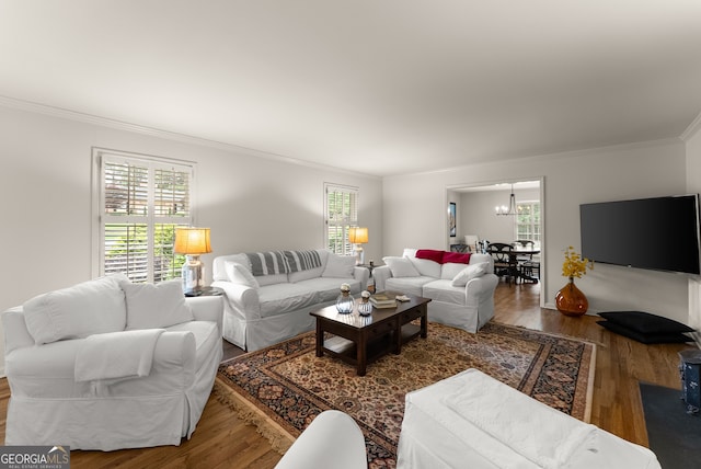 living area with crown molding, wood finished floors, and a chandelier