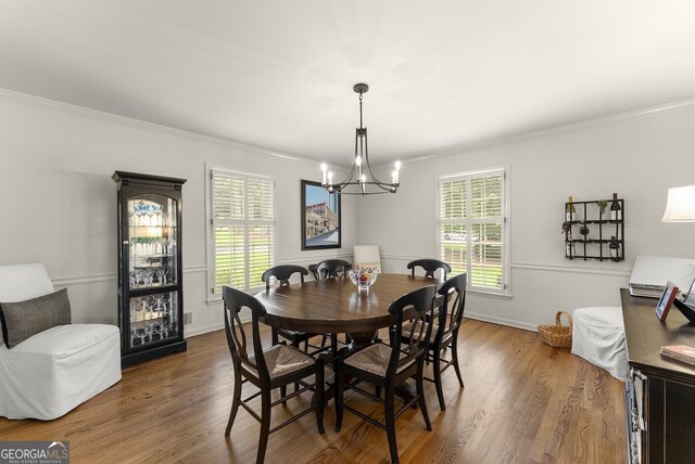 dining room with ornamental molding, a chandelier, wood finished floors, and baseboards