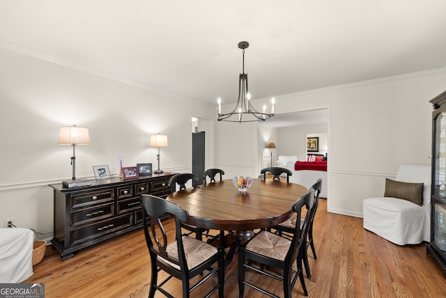 dining area featuring crown molding, light wood-style flooring, and a chandelier