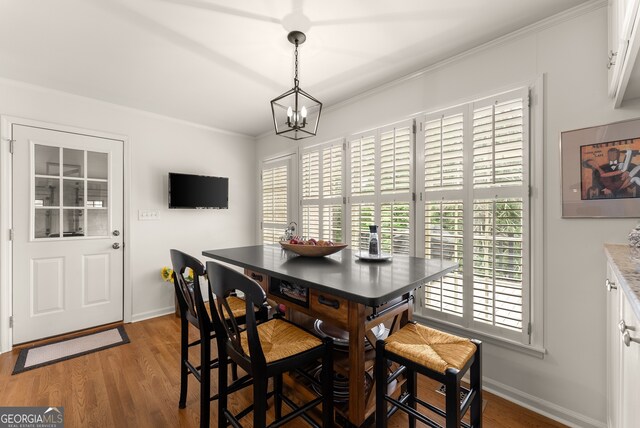 dining area featuring light wood finished floors, baseboards, ornamental molding, and a chandelier