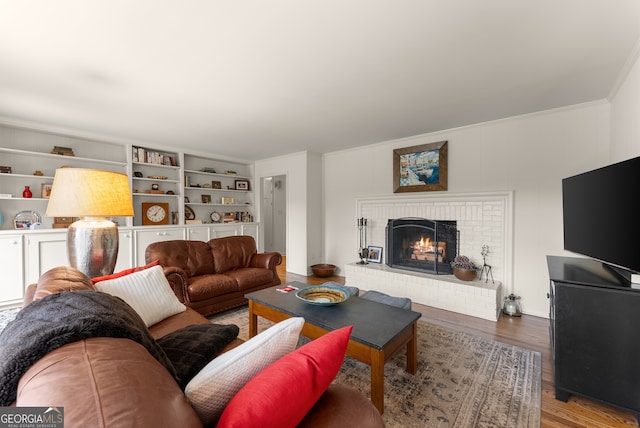 living area featuring wood finished floors, a brick fireplace, and crown molding