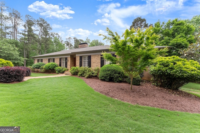 view of front of property featuring brick siding, a front lawn, and a chimney