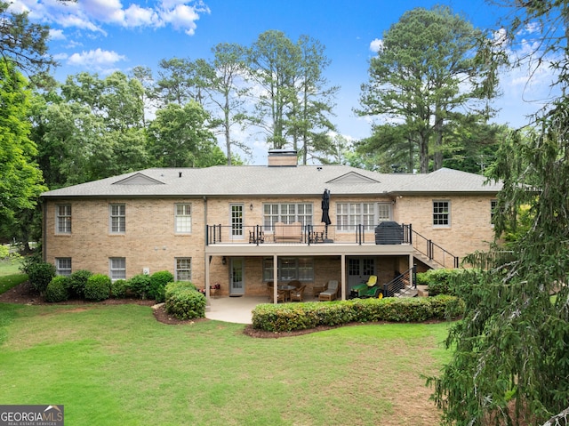 rear view of property featuring a patio, a lawn, stairway, a chimney, and a wooden deck