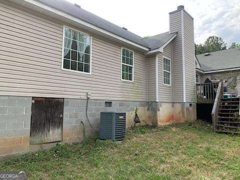 1383 Sims Rd SE, Winder, GA 30680 - view of side of property with a chimney, a lawn, a wooden deck, and central AC unit