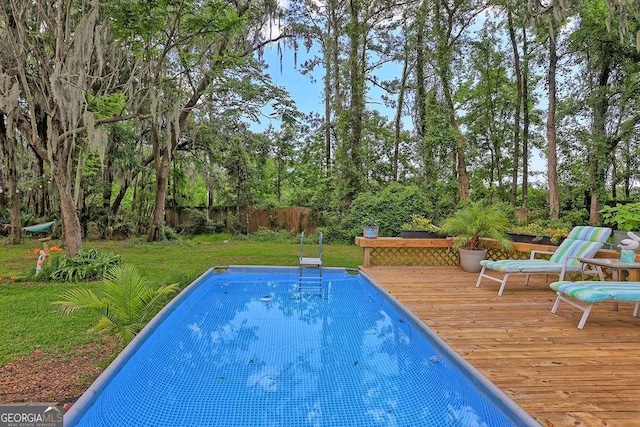 view of pool with a wooden deck and view of scattered trees