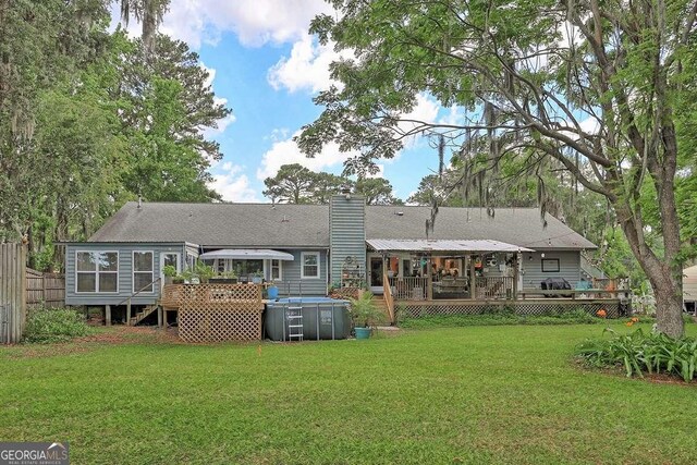 rear view of property featuring a wooden deck, a chimney, and a sunroom