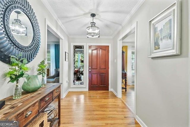 entryway with light wood-style flooring, baseboards, and ornamental molding