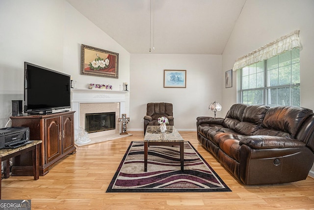 643 Lora Smith Rd, Newnan, GA 30265 - living room with light wood finished floors, a glass covered fireplace, high vaulted ceiling, and baseboards