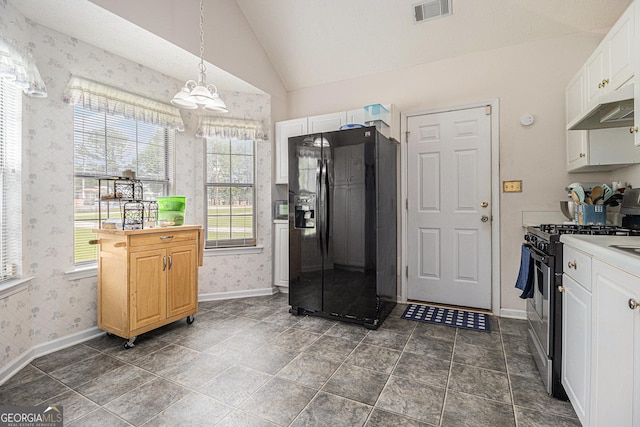 643 Lora Smith Rd, Newnan, GA 30265 - kitchen with black fridge, wallpapered walls, under cabinet range hood, stainless steel gas range oven, and a chandelier