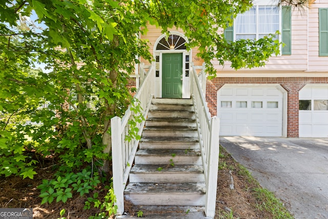 entrance to property featuring brick siding, a garage, and driveway