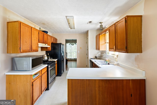 kitchen featuring appliances with stainless steel finishes, under cabinet range hood, light countertops, a peninsula, and a textured ceiling