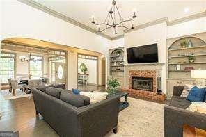 415 Morgan Falls Chase, Canton, GA 30114 - living room featuring a chandelier, crown molding, built in shelves, and a brick fireplace