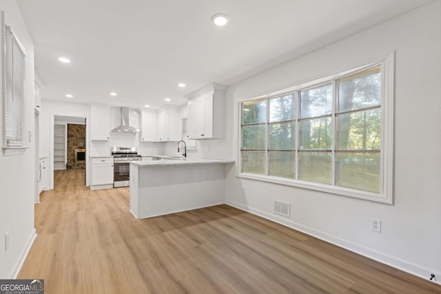 4045 White Oak Ln SW, Lilburn, GA 30047 - kitchen with stainless steel range, wall chimney range hood, a sink, a peninsula, and white cabinets