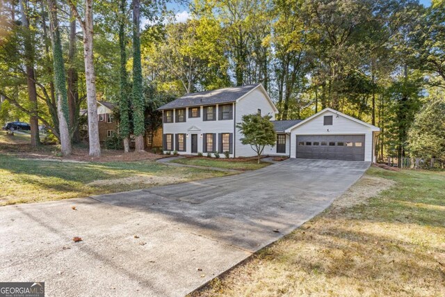 4045 White Oak Ln SW, Lilburn, GA 30047 - colonial home featuring concrete driveway, a garage, a front lawn, and view of scattered trees