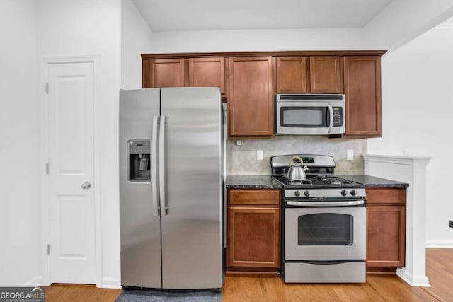 1929 Brightleaf Way, Marietta, GA 30060 - kitchen with appliances with stainless steel finishes, dark stone countertops, light wood-type flooring, backsplash, and brown cabinetry