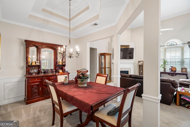 dining area with light carpet, crown molding, a fireplace, wainscoting, and a chandelier