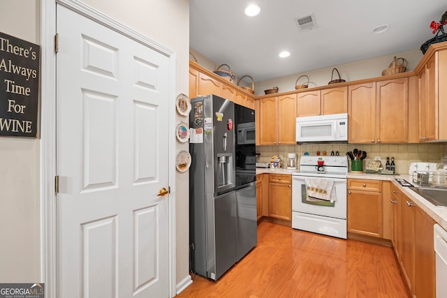 kitchen featuring white appliances, light wood-style flooring, decorative backsplash, light countertops, and recessed lighting